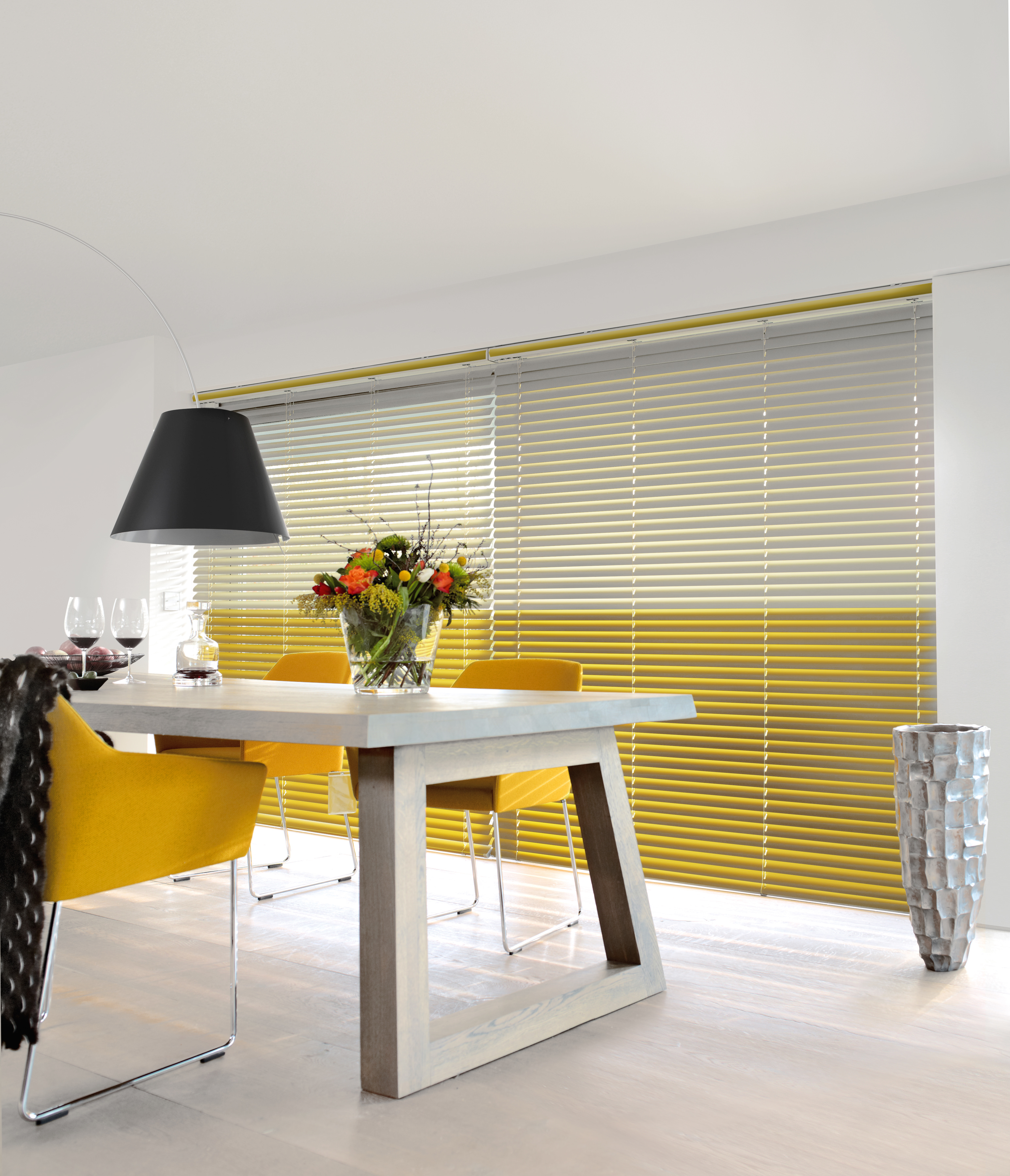 Gelb-graue Jalousien im Esszimmer, moderner Sonnenschutz über die gesamte Fensterfront.