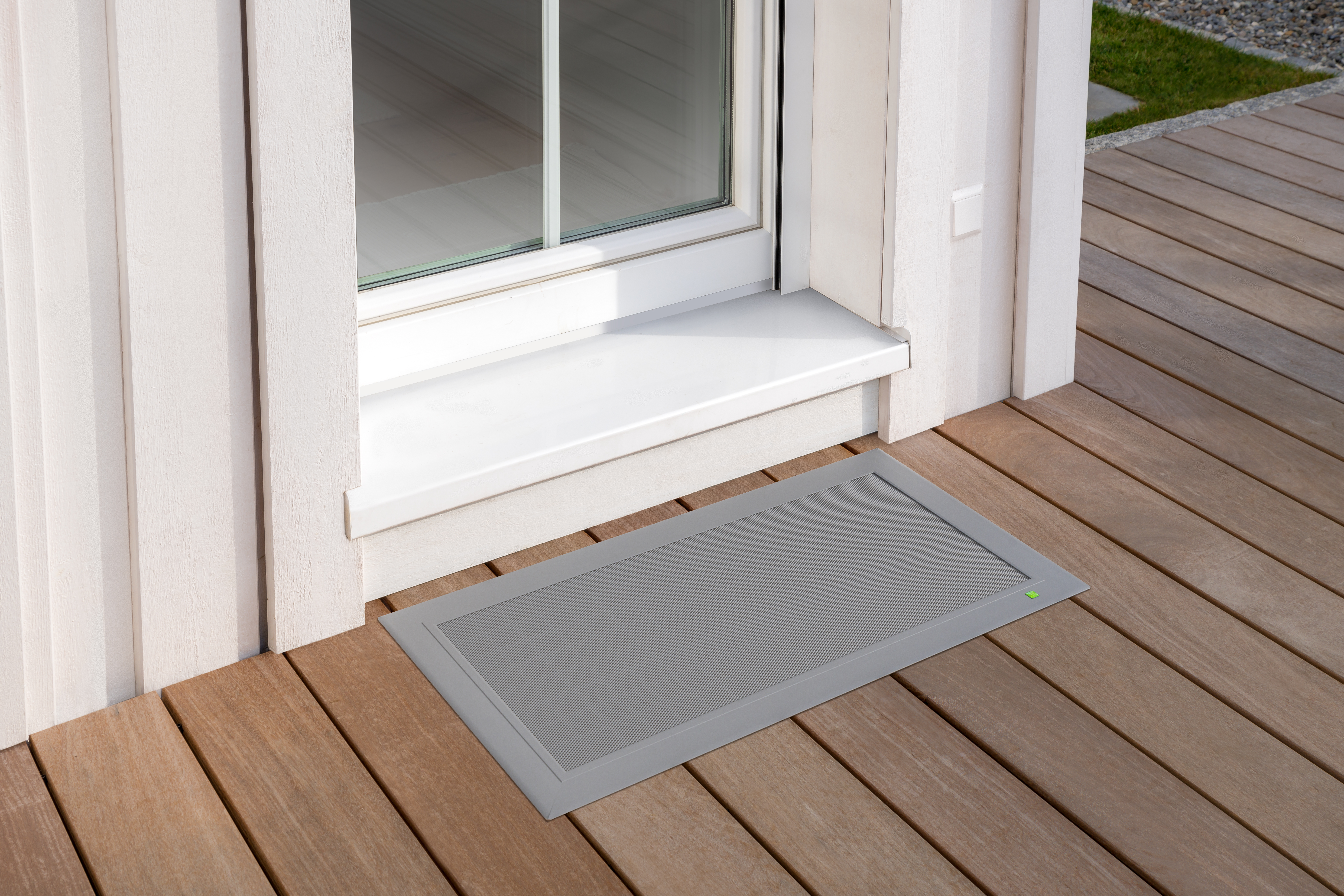 Kellerschachtabdeckung in hellem Aluminiumrahmen auf Holzterrasse unter einer Terrassentür