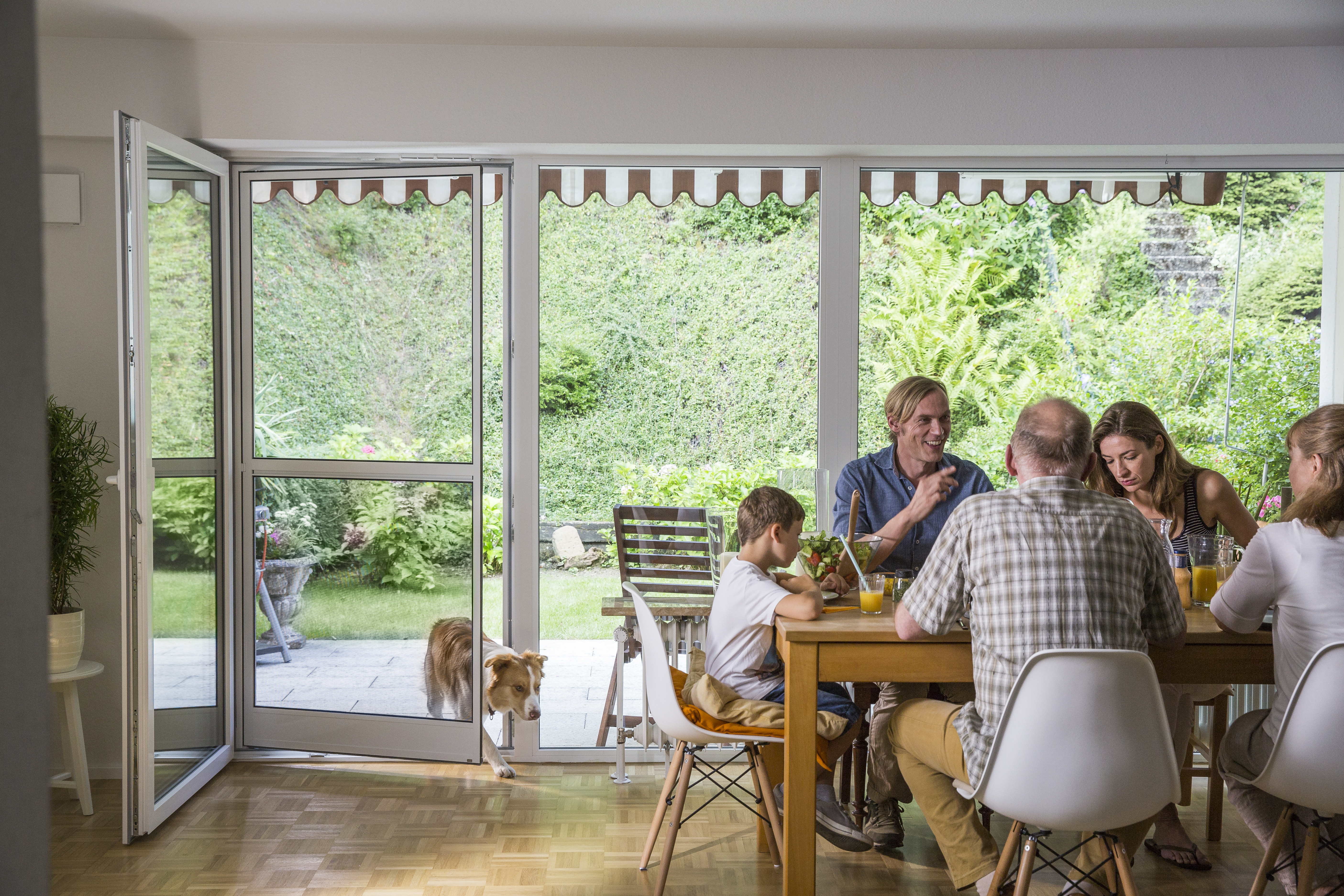 Familie am Esstisch mit Hund, Pendeltür geöffnet für einfachen Durchgang