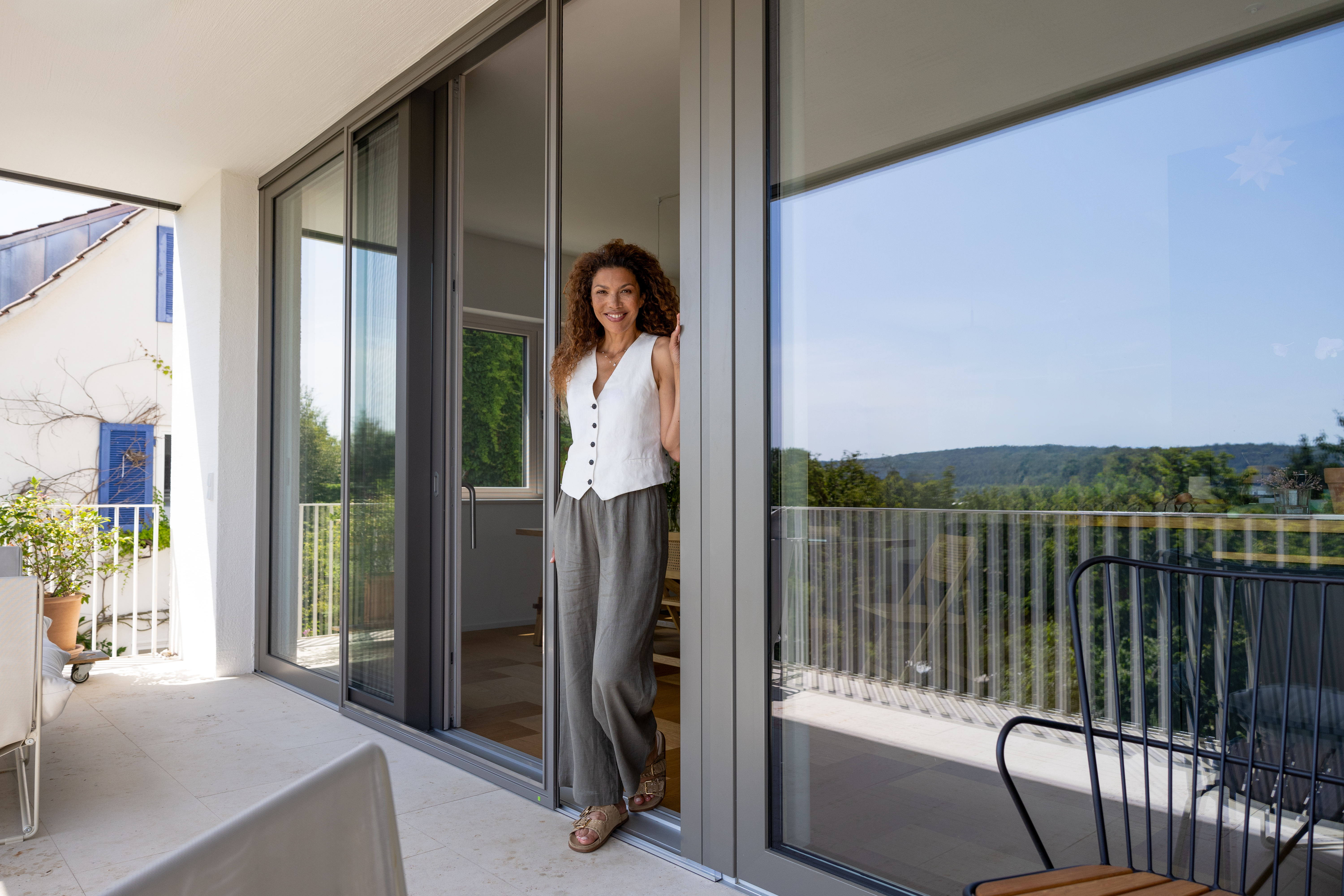 Frau steht in geöffneter Insektenschutz-Schiebetür auf Balkon