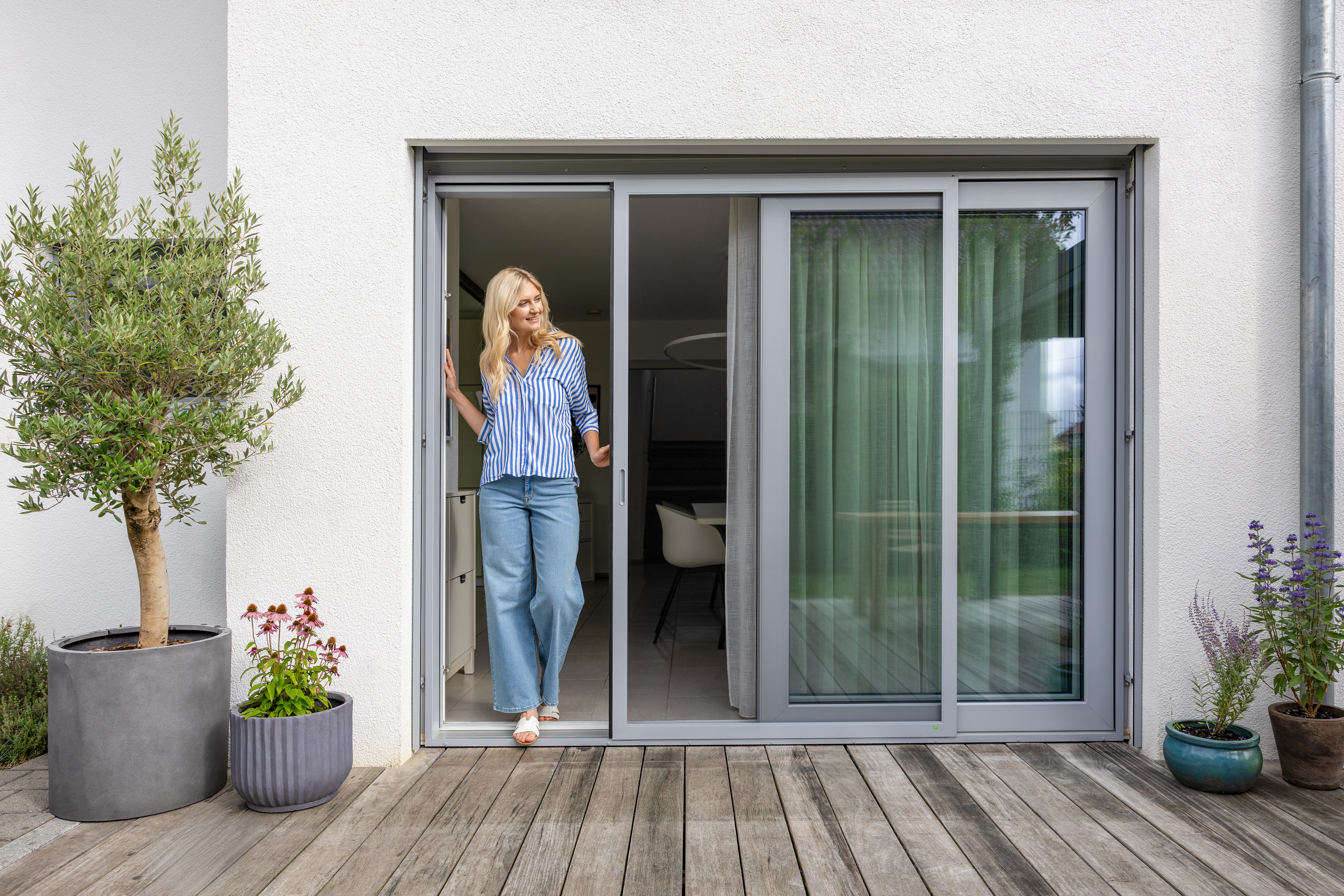 Familie sitzt auf Terrasse, Insektenschutz-Schiebeanlage geöffnet