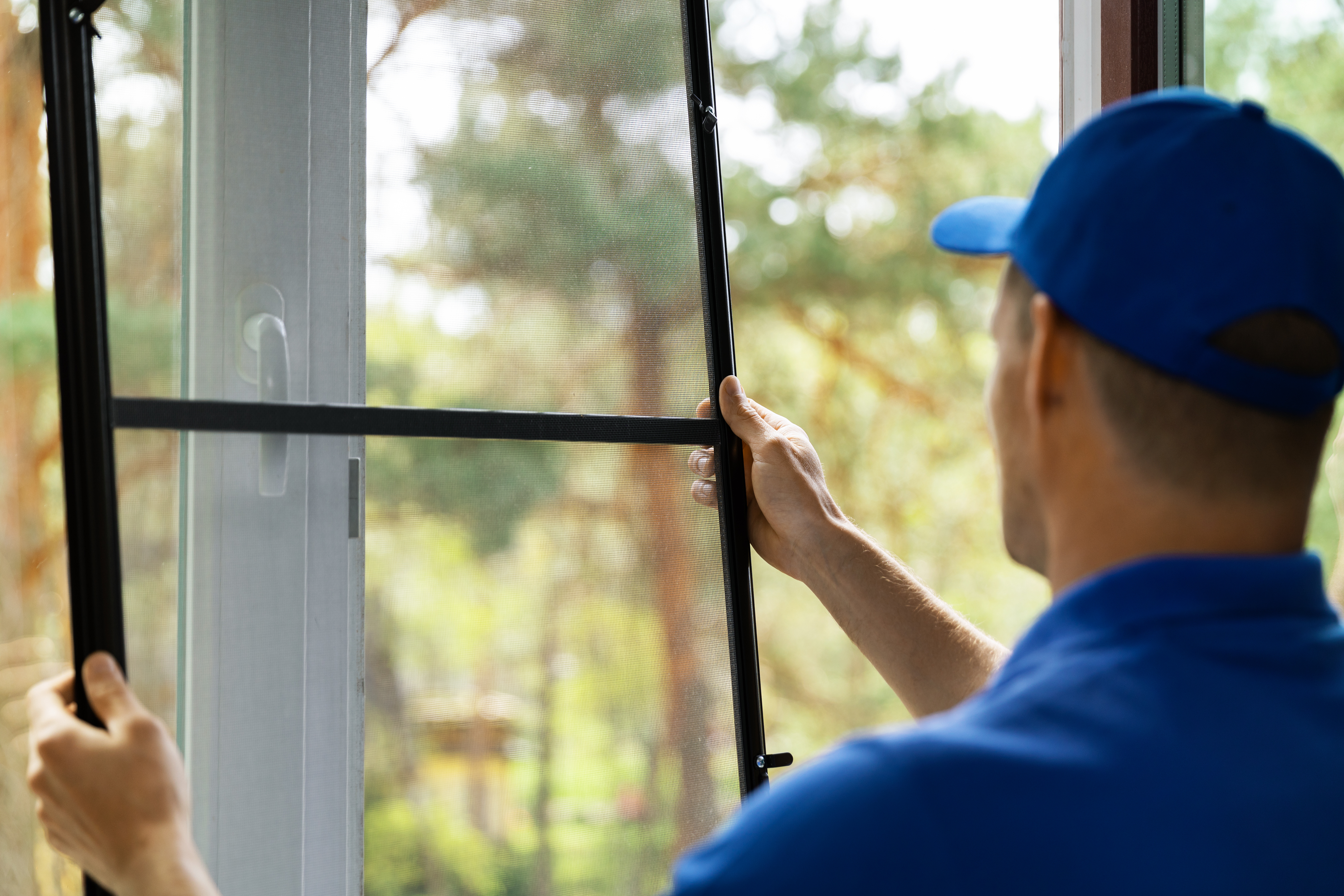 Ein Mann installiert einen Insektenschutz vor dem Fenster